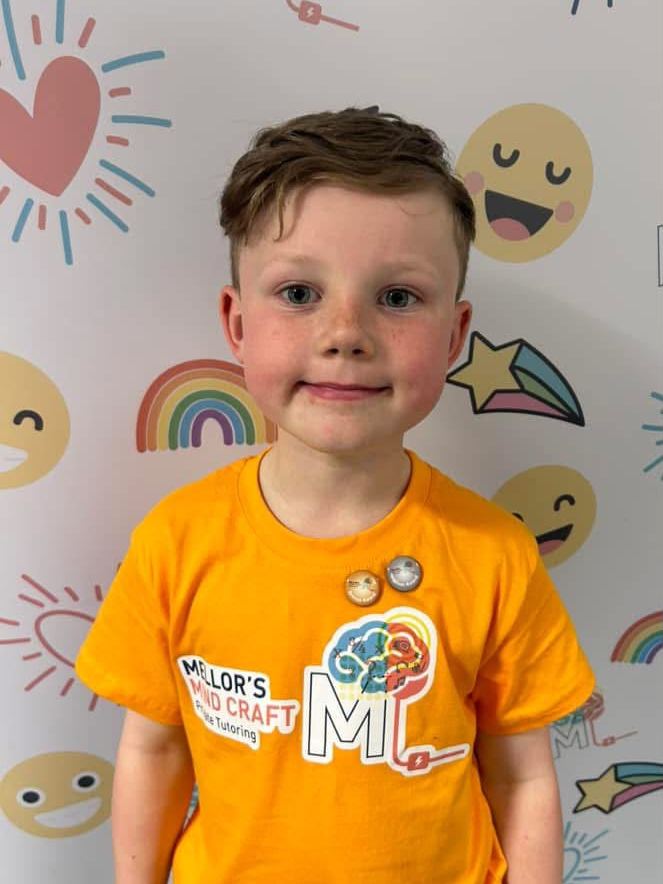 A learner in an orange MMC t-shirt wearing his badges