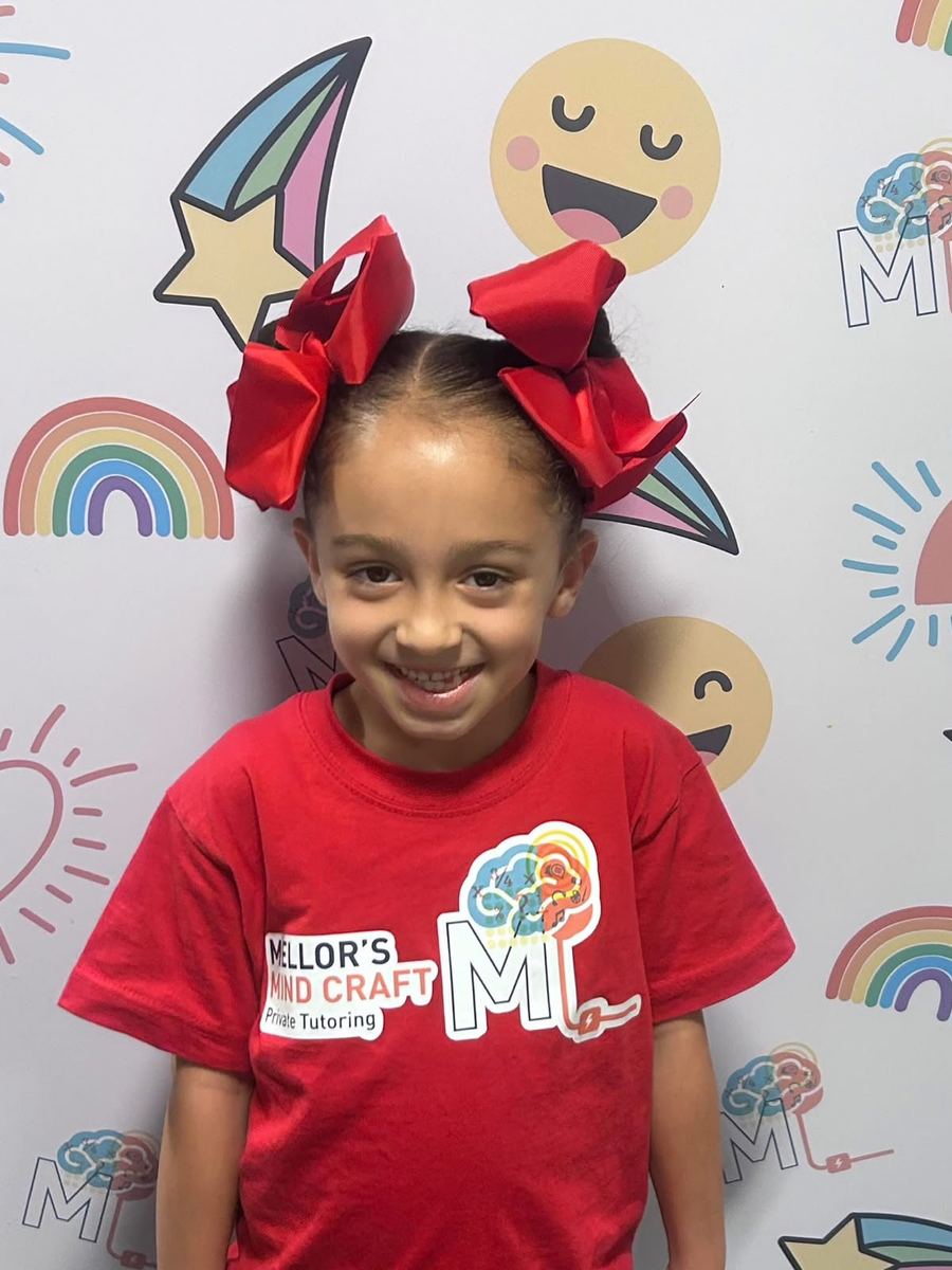 A smiling learner with big red hair bows in an MMC t-shirt